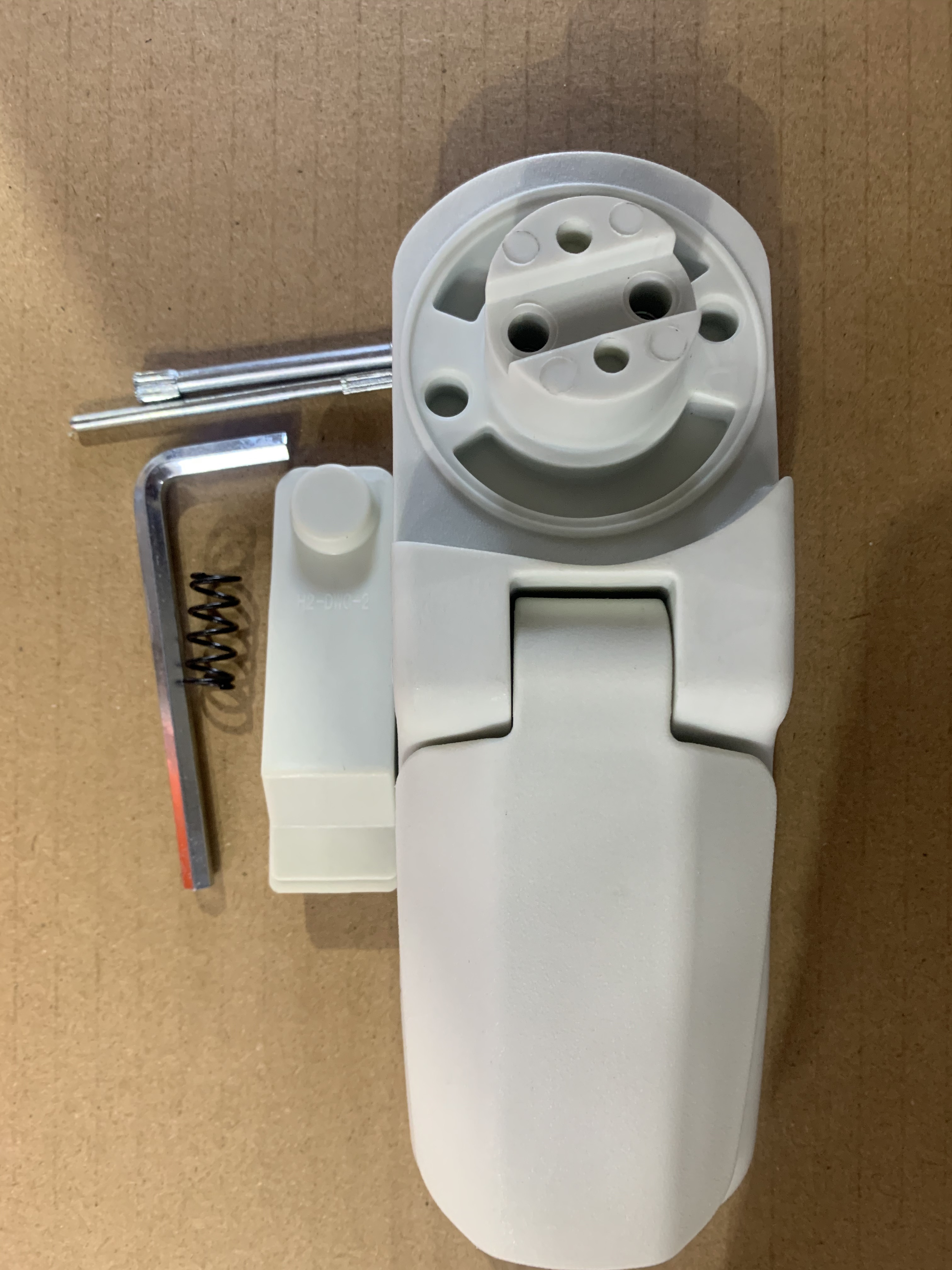Close-up of white automotive power socket with matching plug housing and small metal components including spring, screws, and Allen wrench, gray/white color.