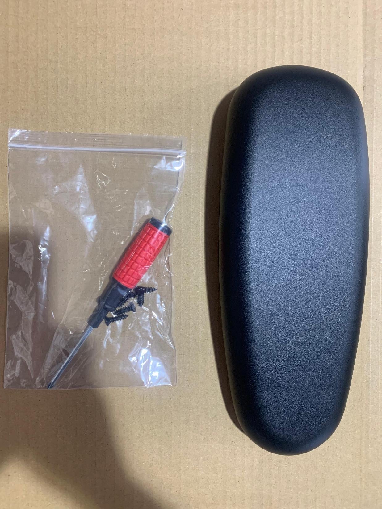 A black car mirror cover and a screwdriver in a plastic bag
